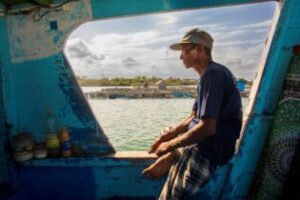 An Indonesian shark fisherman looks over the water from the cabin of his fishing boat.